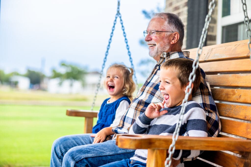 Grandpa making the grandkids laugh on a porch swing